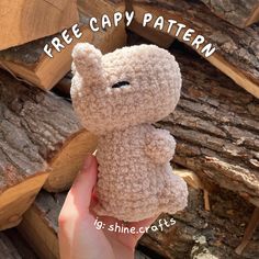 a hand holding a small teddy bear in front of wood logs with the caption free crochet pattern