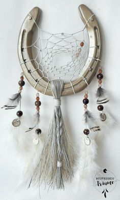 a dream catcher with feathers and beads hanging from it's side on a white wall