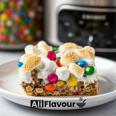 a white plate topped with a slice of cake covered in candy and marshmallows