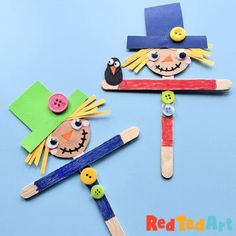 two scarecrows made out of popsicle sticks with buttons and pins on them