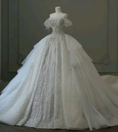 a white wedding dress on display in front of a wall with an ornate design and beading