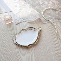 a white and gold plate sitting on top of a table next to a lace curtain