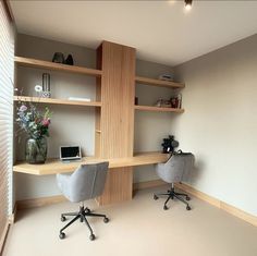 two chairs are in front of a desk with a laptop on it and shelves above the desk