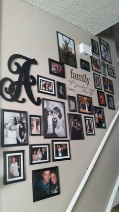 a family photo collage on the wall next to stairs with framed photos and letters