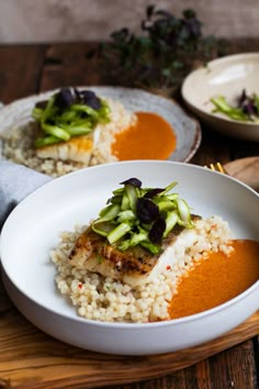 two white plates topped with food on top of a wooden table