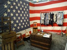 an american flag is hanging on the wall next to two wooden chairs and a chest