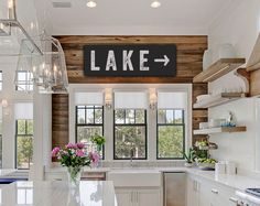 a kitchen with white cabinets and wood paneling on the walls, along with a large center island