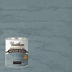 a can of varnishe wood stain on top of a wooden floor with blue paint