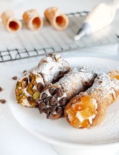 two pastries on a plate covered in powdered sugar and chocolate, sitting next to each other