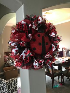 a red and black ladybug wreath hanging on the side of a pillar