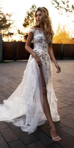 a woman in a white dress standing on a brick floor with her legs spread out