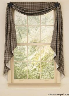 a window with a plaid curtain hanging from it's side and a tree in the background