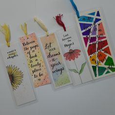 three bookmarks with words and flowers on them hanging from the wall next to each other