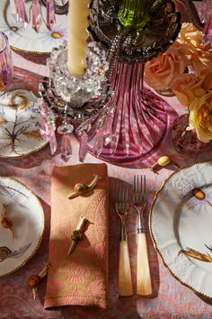 the table is set with plates, silverware and flowers