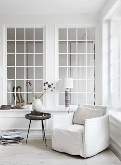 a living room filled with furniture and lots of window panes on the wall above