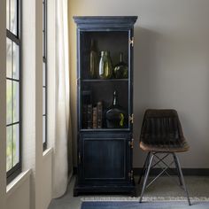 a black bookcase sitting next to a window in a room with a wooden chair