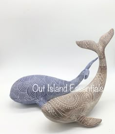 two ceramic whale sculptures sitting next to each other on a white surface with the words out island e written below them