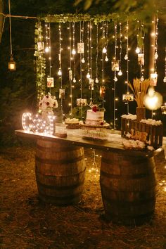 a table that has some cake on it and lights hanging from the trees behind it