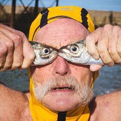 an older man holding up two fish in front of his eyes