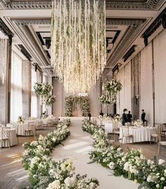 an elegant wedding setup with white flowers and greenery on the floor, chandeliers hanging from the ceiling