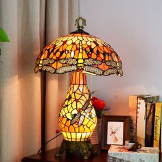 a table lamp sitting on top of a wooden table next to a book shelf and window