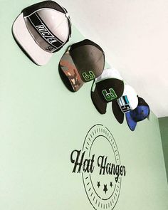 three hats hanging on the side of a wall with stickers attached to it's sides