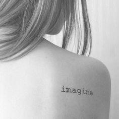 the back of a woman's shoulder with an inscription on it that reads imagine