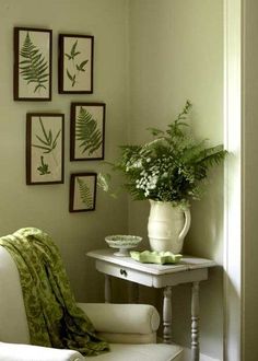 a white chair sitting next to a table with flowers on it in front of pictures