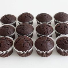 twelve chocolate muffins lined up on a white surface