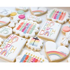 decorated cookies with happy birthday images and candles are displayed on a white tablecloth covered surface