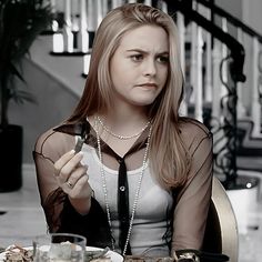 a woman sitting at a table with food in front of her and holding a knife