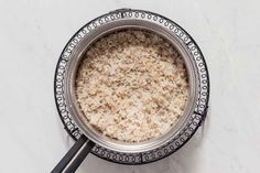 rice in a bowl with two spoons on the side and white marble counter top