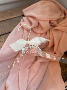 a pink scarf with pearls and a name on it