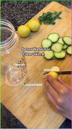 a person cutting up cucumbers on top of a wooden cutting board next to a mason jar