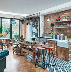 a kitchen with an island and lots of stools in it, next to a brick wall