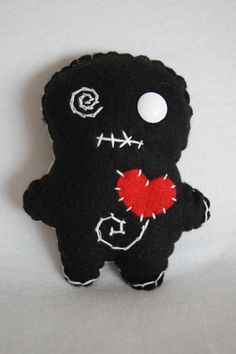 a black teddy bear with a red heart on it's chest and eyes painted white