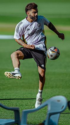 a man kicking a soccer ball on top of a field