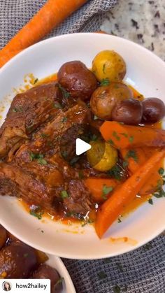 a white plate topped with meat and veggies next to carrots on a table