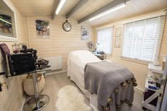 a bedroom with a bed, desk and window in it's center area that has white shutters on the windows