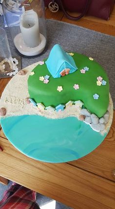 a birthday cake that is shaped like a golf course on the beach with rocks and grass