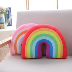 two rainbow pillows sitting on top of a white chair