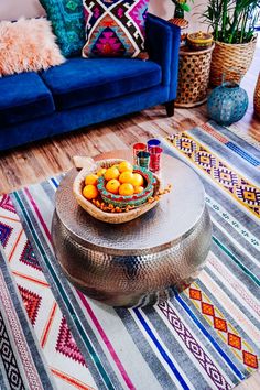 a living room with a blue couch and colorful rugs on the floor next to a coffee table