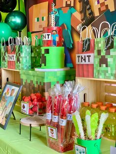 a table topped with lots of green and red items next to a wall covered in balloons