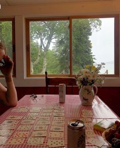 a woman sitting at a table talking on a cell phone and drinking from a cup