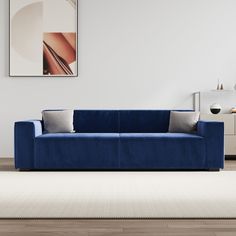 a blue couch sitting on top of a wooden floor next to a white rug in a living room