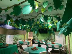 a room with tables and chairs covered in green cloths, hanging from the ceiling