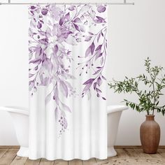 a white bath tub sitting next to a shower curtain with purple flowers on the side