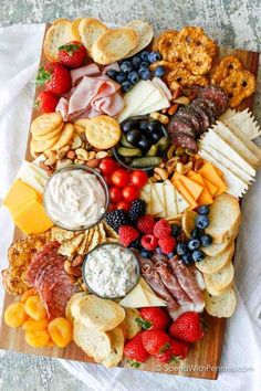 an assortment of cheeses, crackers and nuts arranged in the shape of a heart