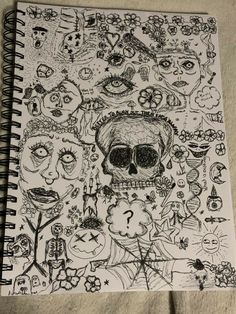 a spiral notebook with drawings on it and an image of a skull in the middle