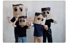 three children wearing paper masks with their hands in the air